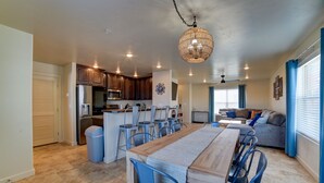 Een moderne keuken met donkere houten kastjes, een centraal eiland met barstoelen en een hangende lamp.