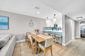 A modern kitchen with a blue backsplash, wooden dining table, and pendant lights. - Summerhaven 3 | Beach Front Townhome with Free Chairs through October! | New Coastal Design! | Tail-Wagging Approved (Miramar Beach)