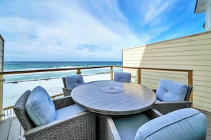 Une terrasse dotée d’une table ronde et de chaises en osier, offrant une vue sur l’océan.