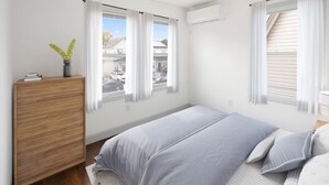 A bedroom with a bed, a wooden dresser, and a window with curtains.