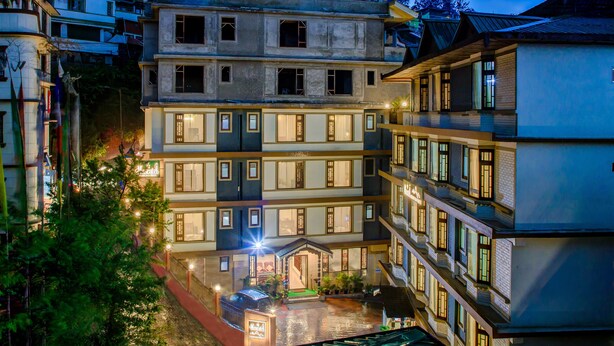 A multi-story hotel with a courtyard, balconies, and a well-lit entrance. - Muscatel Grand Silkroute 300 Mts MG Marg (Gangtok)
