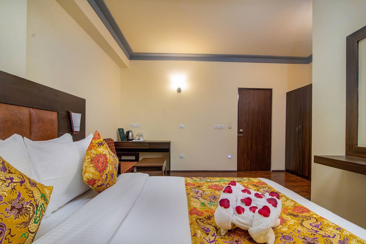 Une chambre d’hôtel comprenant un lit, des oreillers, une table de chevet, une lampe, une porte et un luminaire fixé au mur.