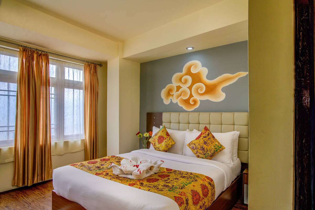Une chambre d’hôtel avec un lit, des rideaux, une fresque murale et une fenêtre.
