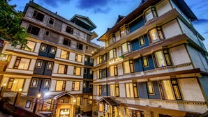 A multi-story hotel with a courtyard, balconies, and illuminated windows. - Muscatel Grand Silkroute 300 Mts MG Marg (Gangtok)