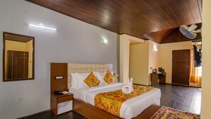 A hotel room with a wooden bed, bedside tables, a nightstand, a wall-mounted light, and a ceiling fan. - Muscatel Grand Silkroute 300 Mts MG Marg (Gangtok)