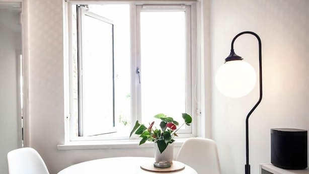 A room with a round white table, two white chairs, a potted plant, a black floor lamp, and a bookshelf with books. - Lovely 1Bed Flat - Green Lanes - Spacious and Quiet (Greater London)