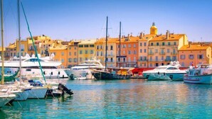 A marina with several boats docked, surrounded by colorful buildings with balconies.