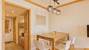 A cozy room with a wooden dining table and four chairs, a bunk bed, and a hanging light fixture.