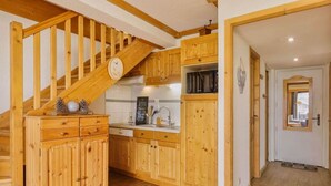 A wooden staircase leading to a kitchen with wooden cabinets and a built-in microwave.