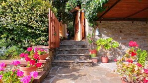 A stone staircase leading to a wooden door, surrounded by potted plants and flowers. - Panoramic small house with private pool, situated in the hills above Cortona. Set in a quiet and sec (Cortona)