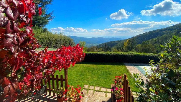 A garden with a wooden fence, a lawn, and a view of distant mountains. - Panoramic small house with private pool, situated in the hills above Cortona. Set in a quiet and sec (Cortona)