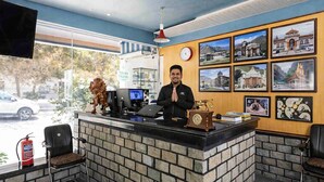 Un comptoir d’accueil avec une horloge, une statue de lion et des tableaux encadrés accrochés au mur.