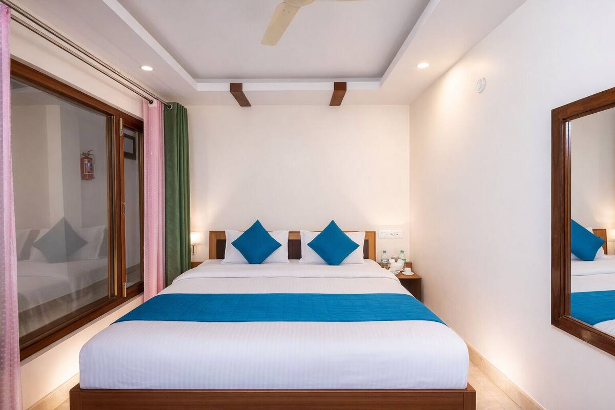 A hotel room with a bed, nightstand, and a mirror.