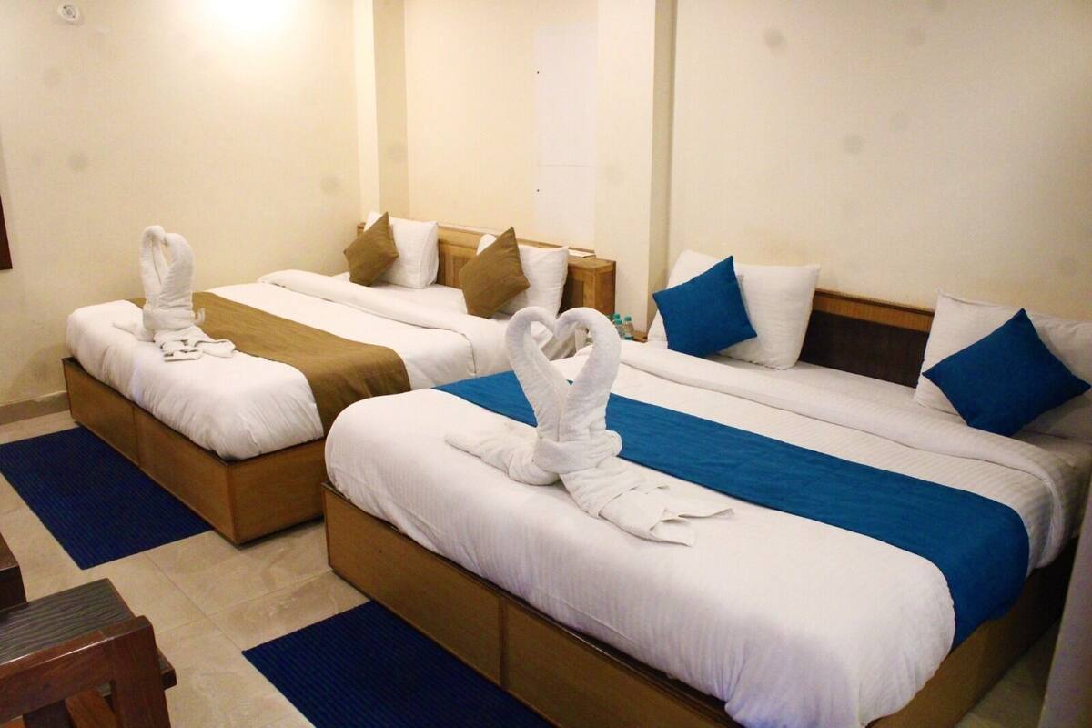 A hotel room with two beds, each with a towel and pillow.
