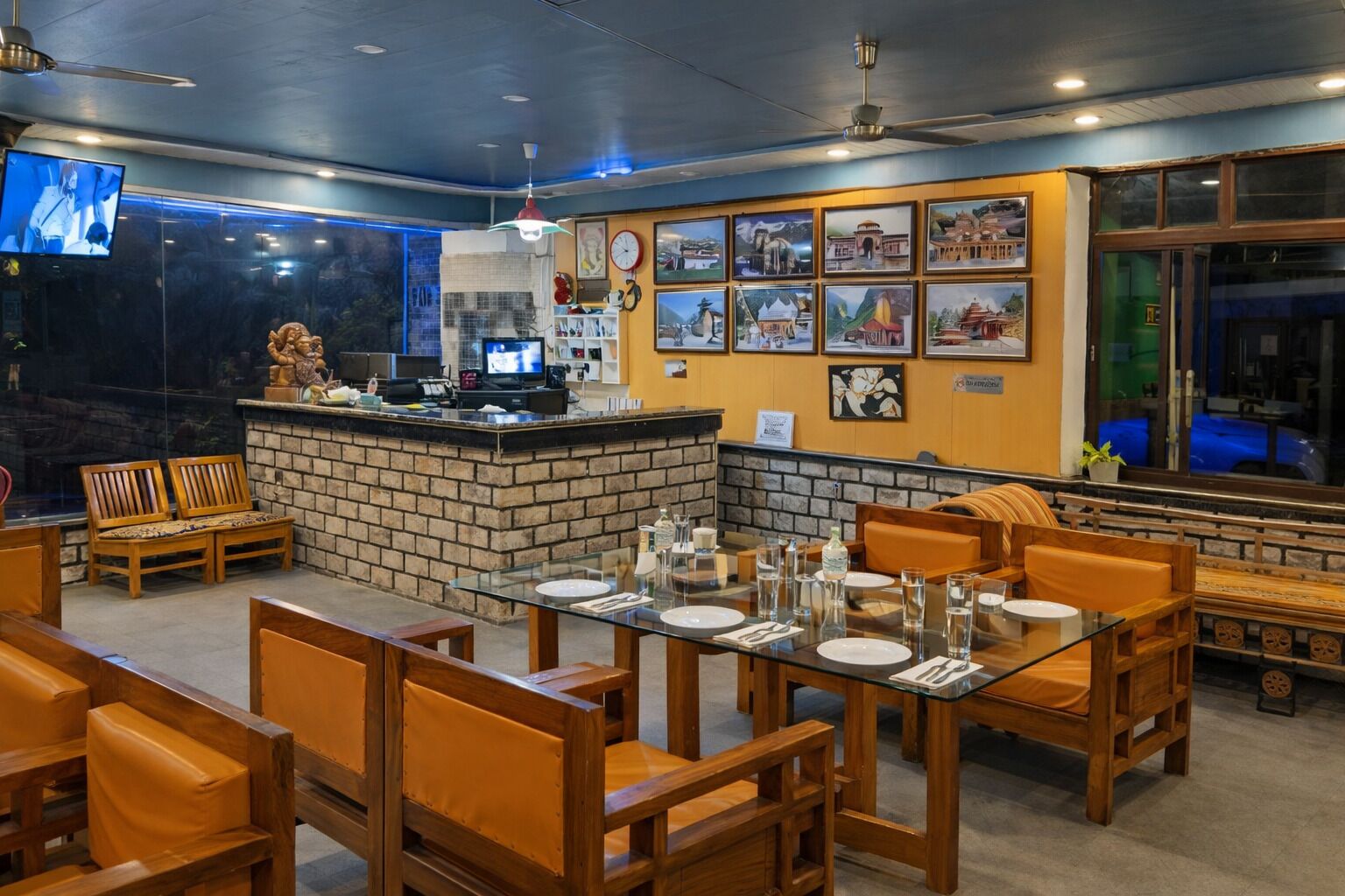 A restaurant with a brick counter, wooden chairs, and tables set for dining.