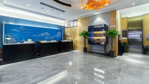 A modern reception area with a blue mural, a reception desk, a plant, and an elevator.