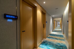 Un pasillo de hotel con puertas de madera, alfombra azul y un cartel que indica la habitación 8603.