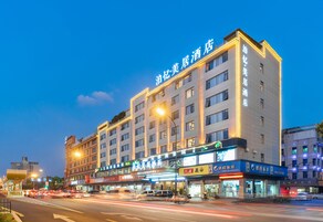 Un hotel de varios pisos con señalización iluminada y una fila de tiendas en la planta baja.