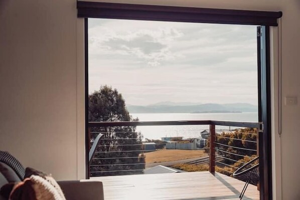 A balcony with a view of a body of water and distant mountains.