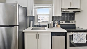 Una cocina moderna con electrodomésticos de acero inoxidable, armarios blancos, un ventanal con vistas y salpicadero de azulejos.