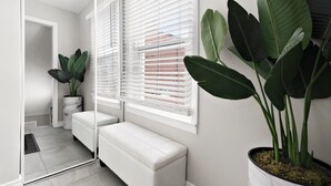 Un baño moderno con sanitarios blancos, un banco y plantas verdes grandes.