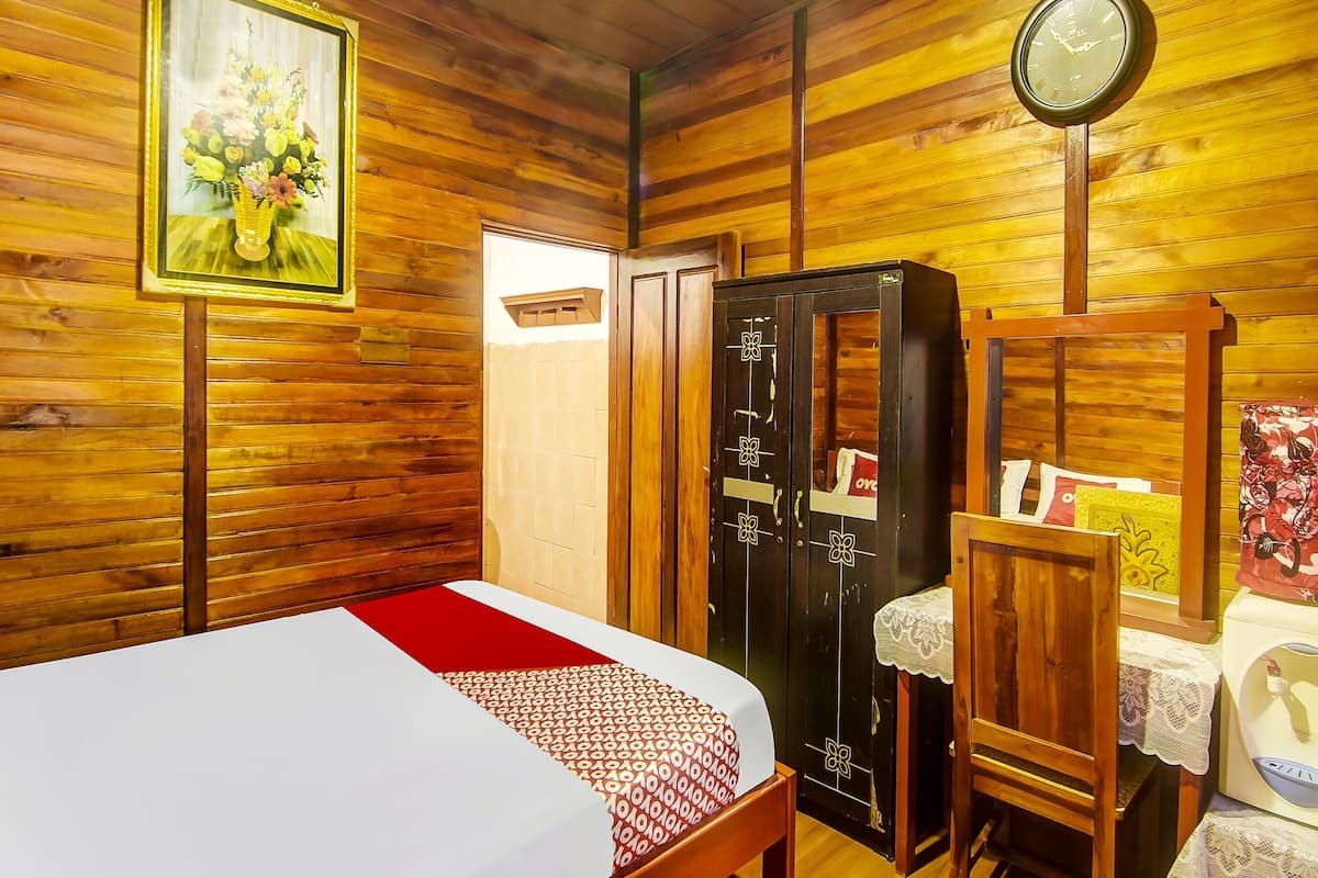 Ein Zimmer mit Holzwänden, einem Bett, einem Kleiderschrank, einer Uhr und einem gerahmten Blumenbild.
