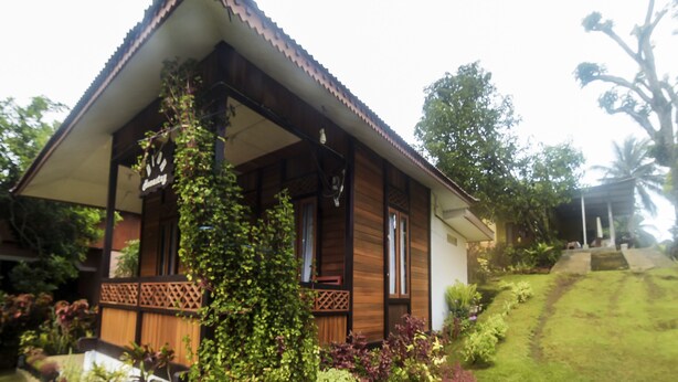 Ein Holzhaus mit Ziegeldach, umgeben von üppiger Vegetation und einem gepflegten Garten.
