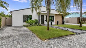 Een modern huis met twee verdiepingen, een verzorgd gazon, een grindpad en een houten omheining.