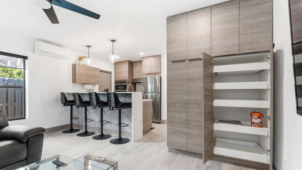 Een moderne keuken met een vast kookeiland, barstoelen en een koelkast.