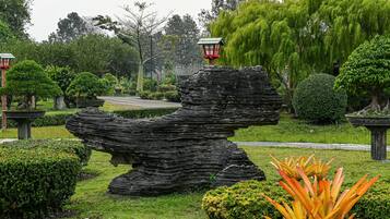 A garden with a large rock formation, a pathway, and various plants.