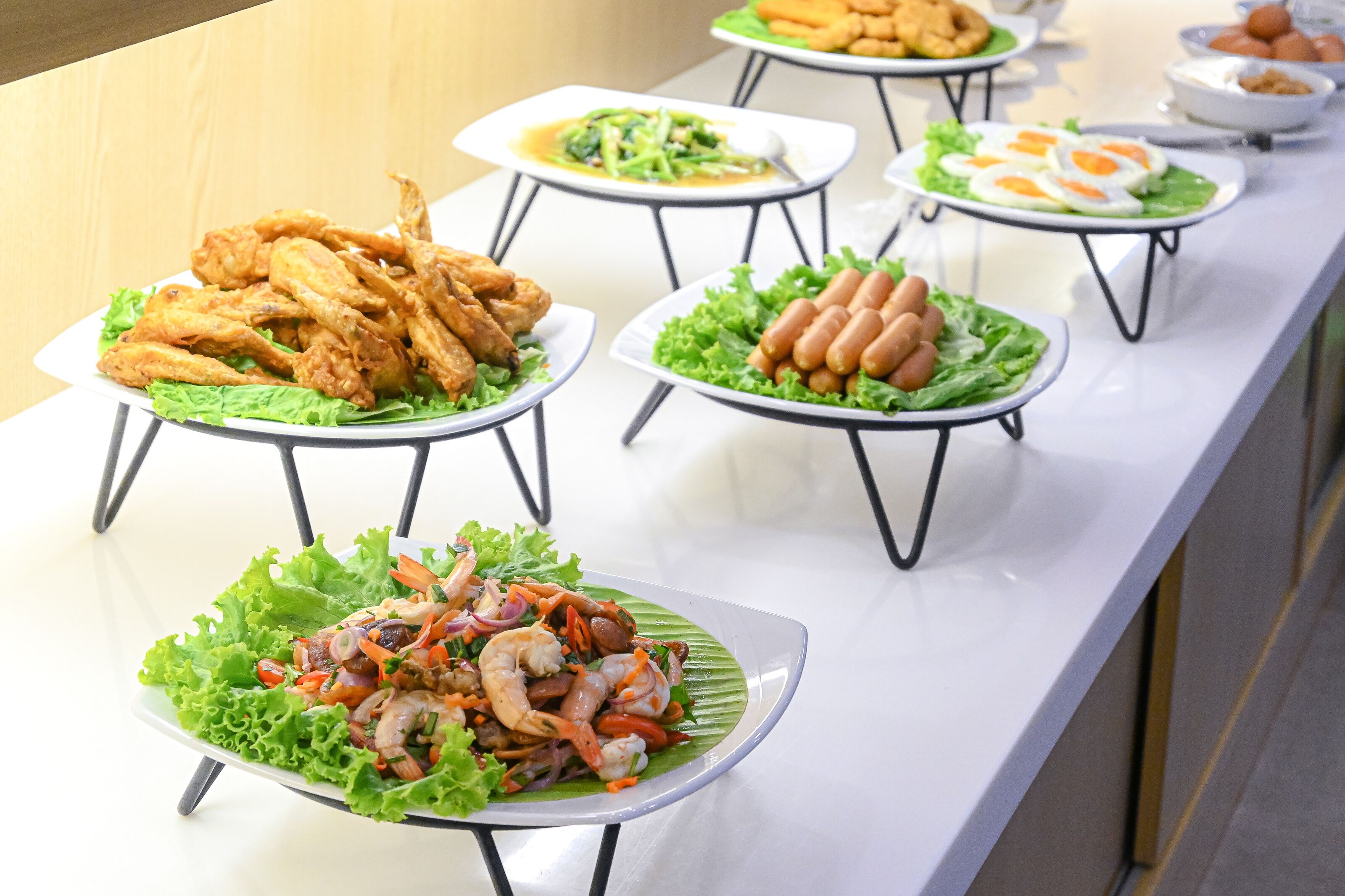 Ein reichhaltiges Buffet mit verschiedenen Speisen, darunter gebratenes Hähnchen, Würstchen und einem Seafood-Salat.
