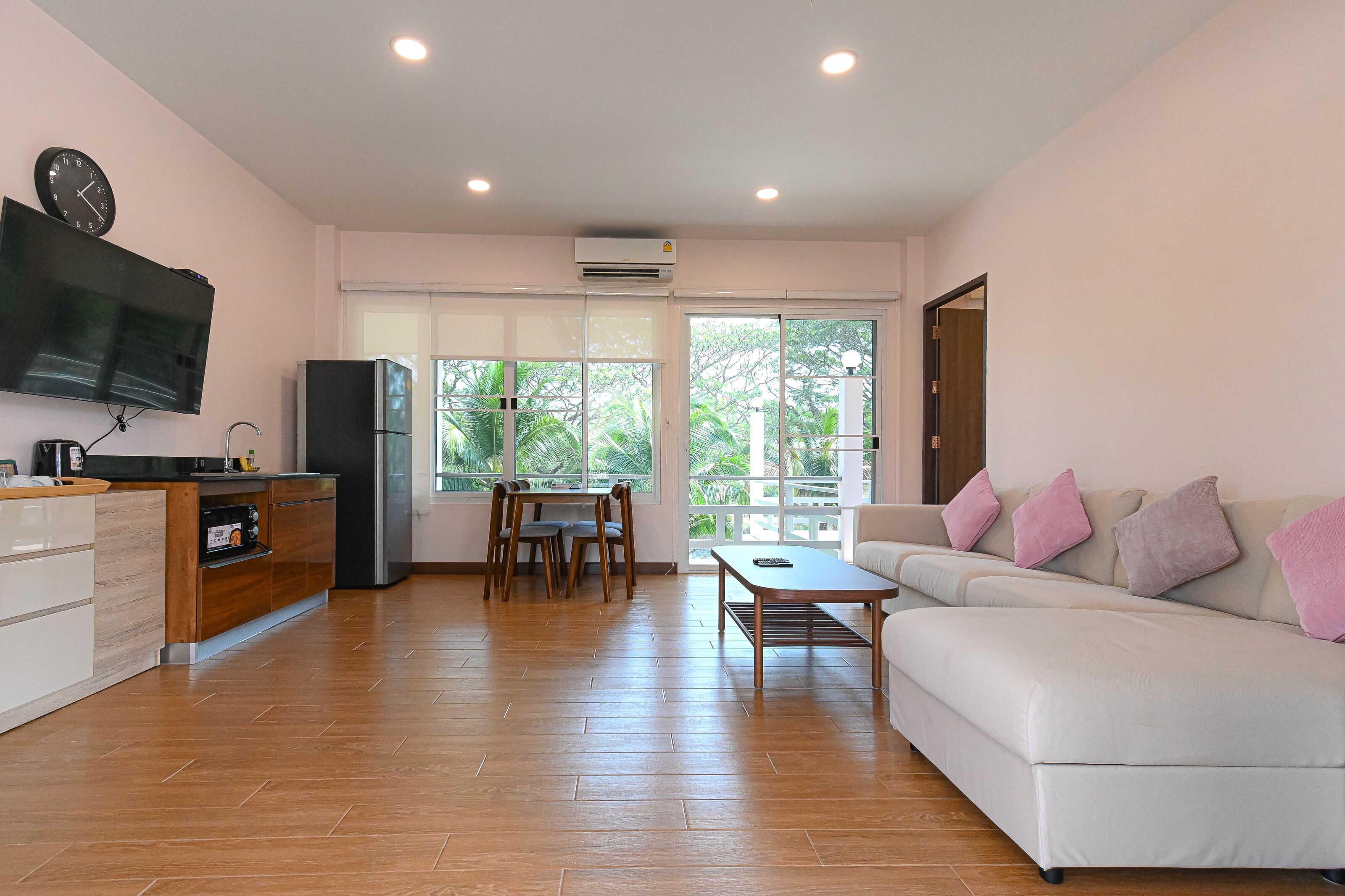 A modern living room with a sofa, a dining table, and a kitchen area.