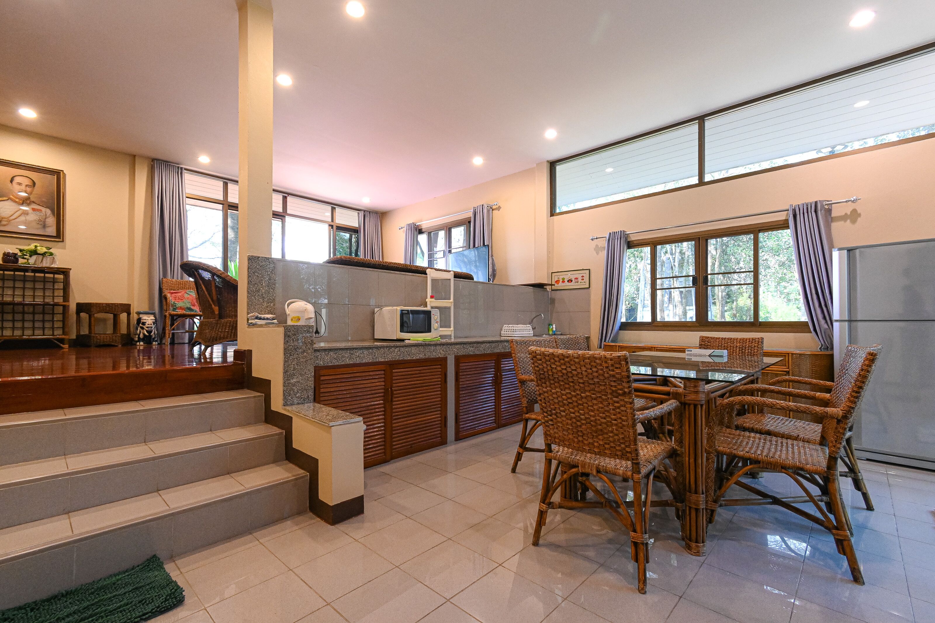 Una cocina moderna con comedor, que incluye una isla de cocina, microondas y sillas de mimbre.