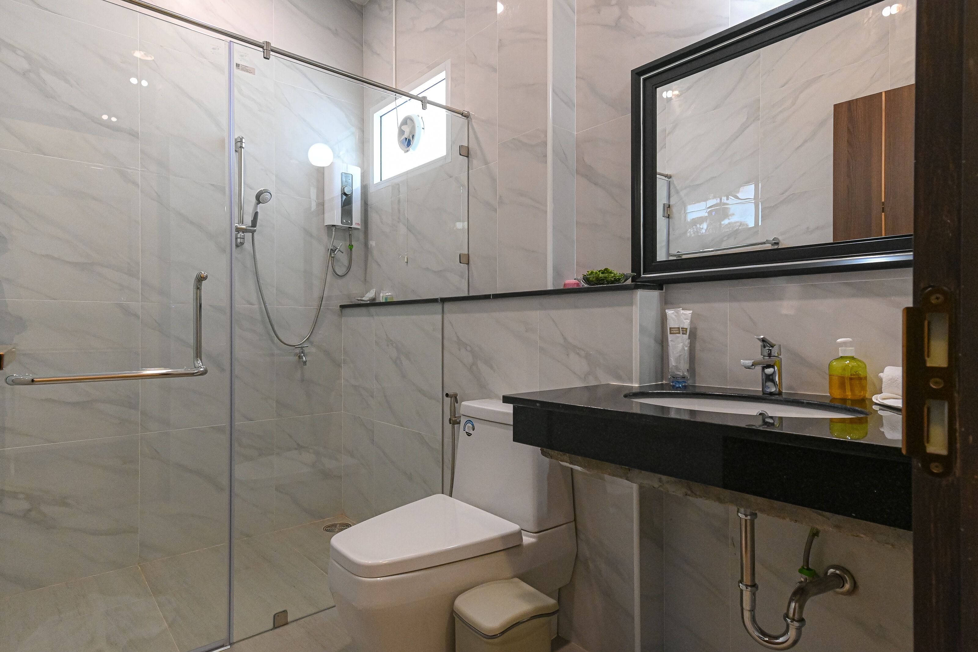 Un bagno moderno con doccia vetrata, un water e un lavandino con specchio sopra.