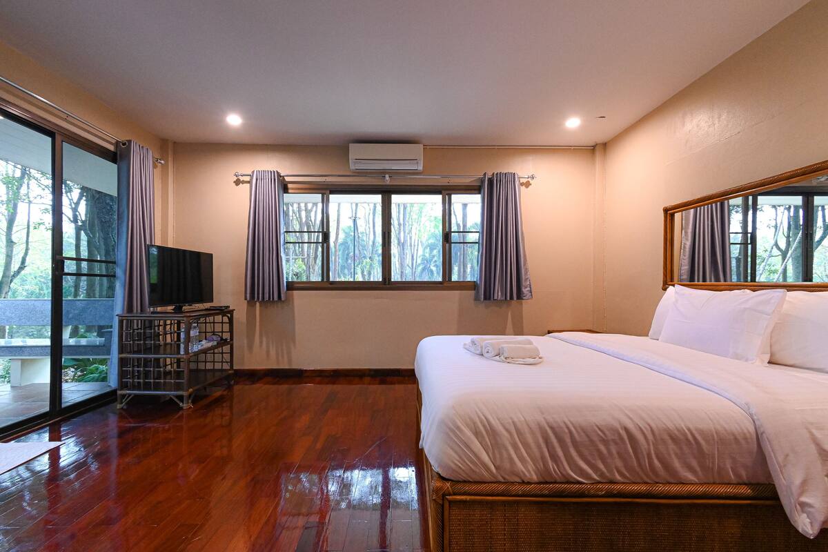 A hotel room with a large bed, a television, and a window with curtains.
