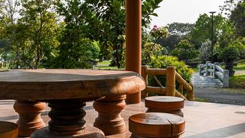 A round table with wooden legs and a matching stool in a garden setting.