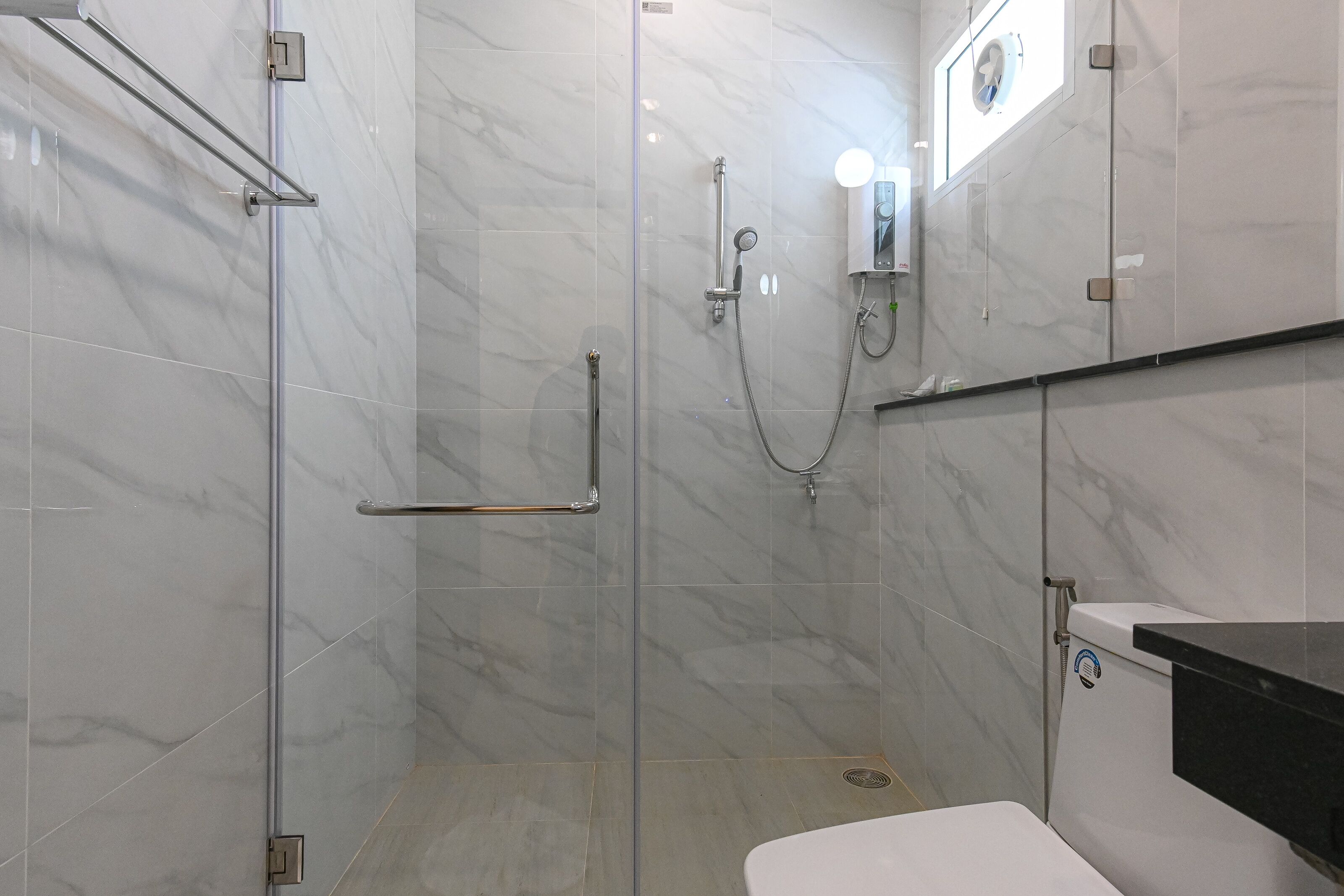 A modern bathroom with a glass shower enclosure, a toilet, and a sink with a black countertop.