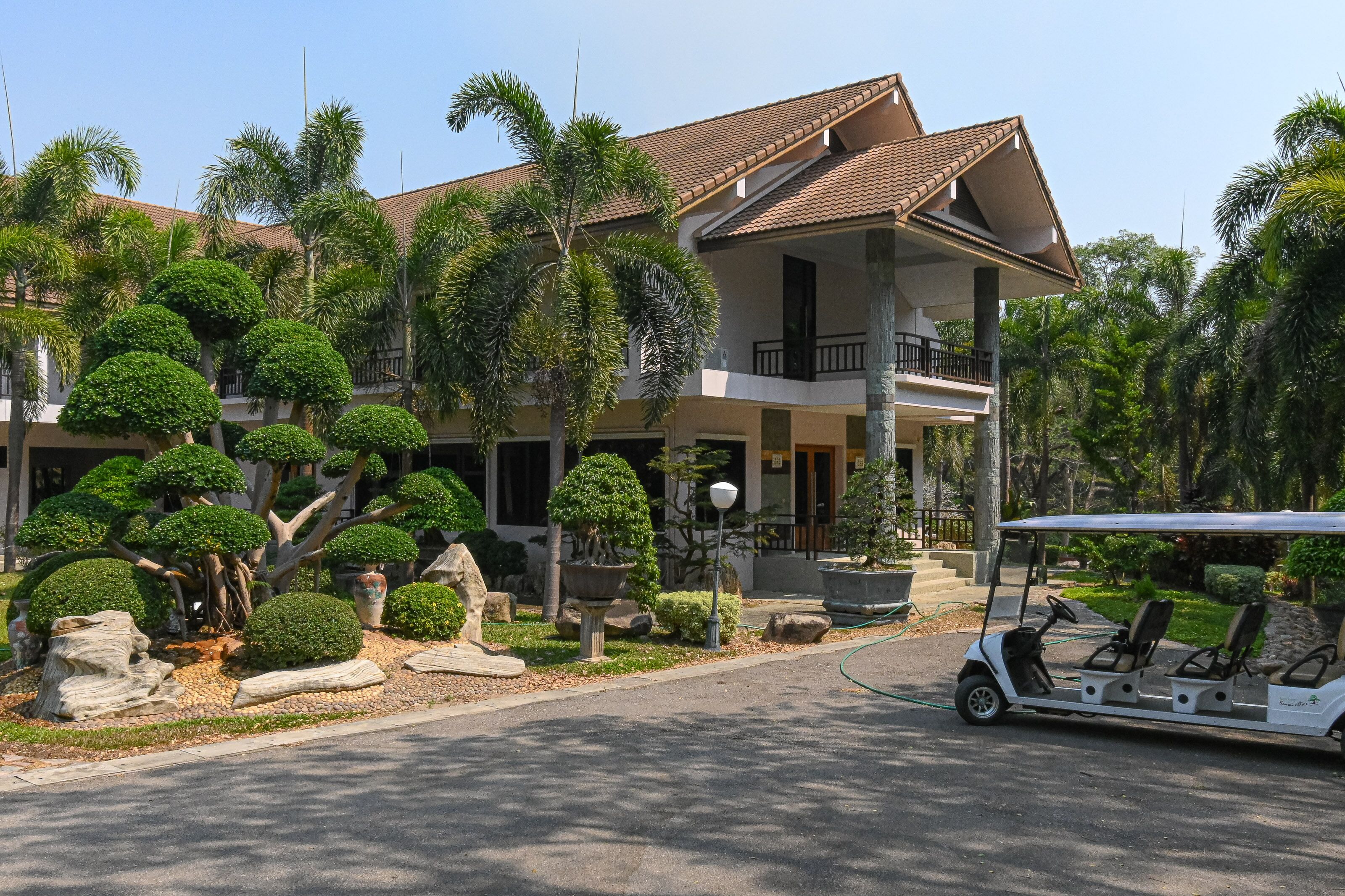 A two-story building with a balcony, surrounded by well-maintained landscaping and a golf cart.