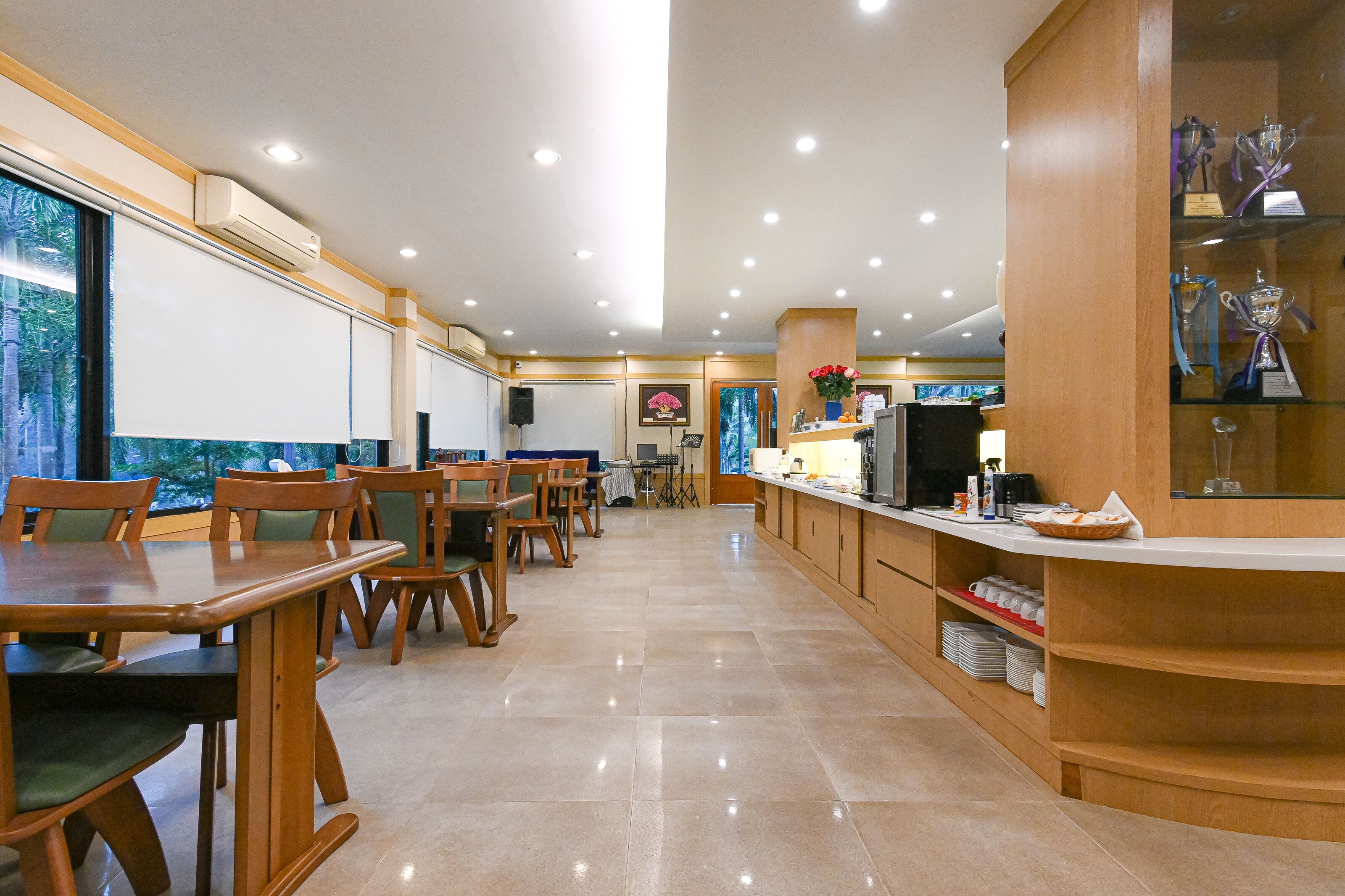 A spacious hotel lobby with wooden furniture, a reception desk, and a display of trophies.