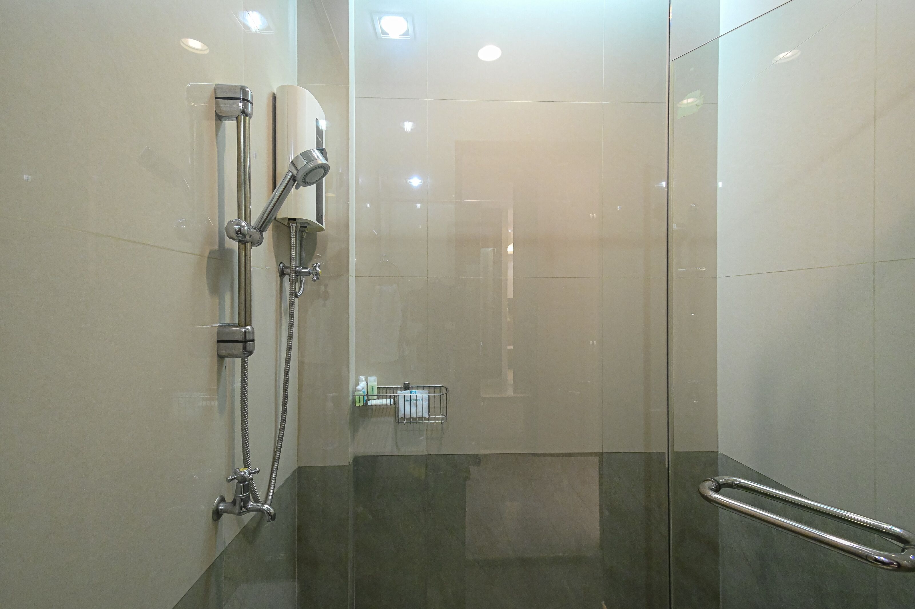 A modern shower with a handheld showerhead, a wall-mounted faucet, and a glass shower enclosure.