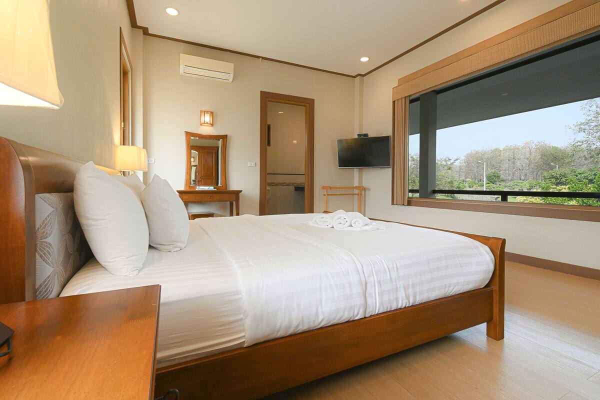 A neatly made bed with white linens, a wooden headboard, and a bedside table with a lamp.