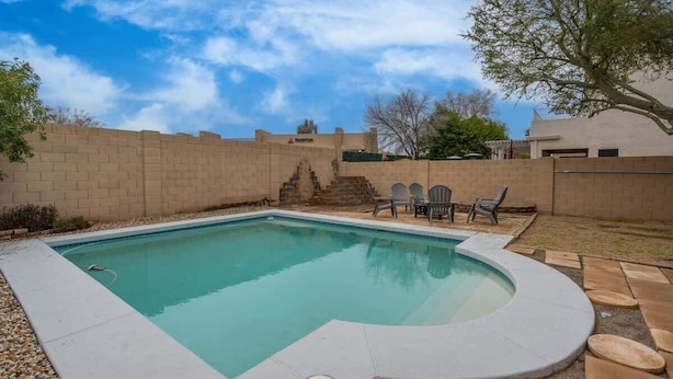 Una piscina con hidromasaje integrado, rodeada por un muro de ladrillo y una zona de patio con mobiliario exterior.