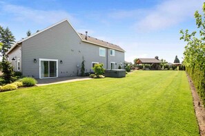 A two-story house with a well-maintained lawn, a patio area, and a small garden. - Spectacular Villa on 25 Acre Orchard, Pergola w/ Fireplace, Private Hot Tub, Pet Friendly, BBQ (Aurora)