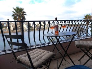 Ein Balkon mit Tisch, zwei Stühlen und einer Weinflasche.