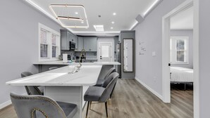 A modern kitchen with a central island, grey upholstered chairs, and a white countertop. - Spacious 3BR House in Charlotte (Charlotte)