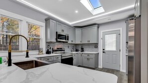 A modern kitchen with a large island, grey cabinetry, and a skylight. - Spacious 3BR House in Charlotte (Charlotte)