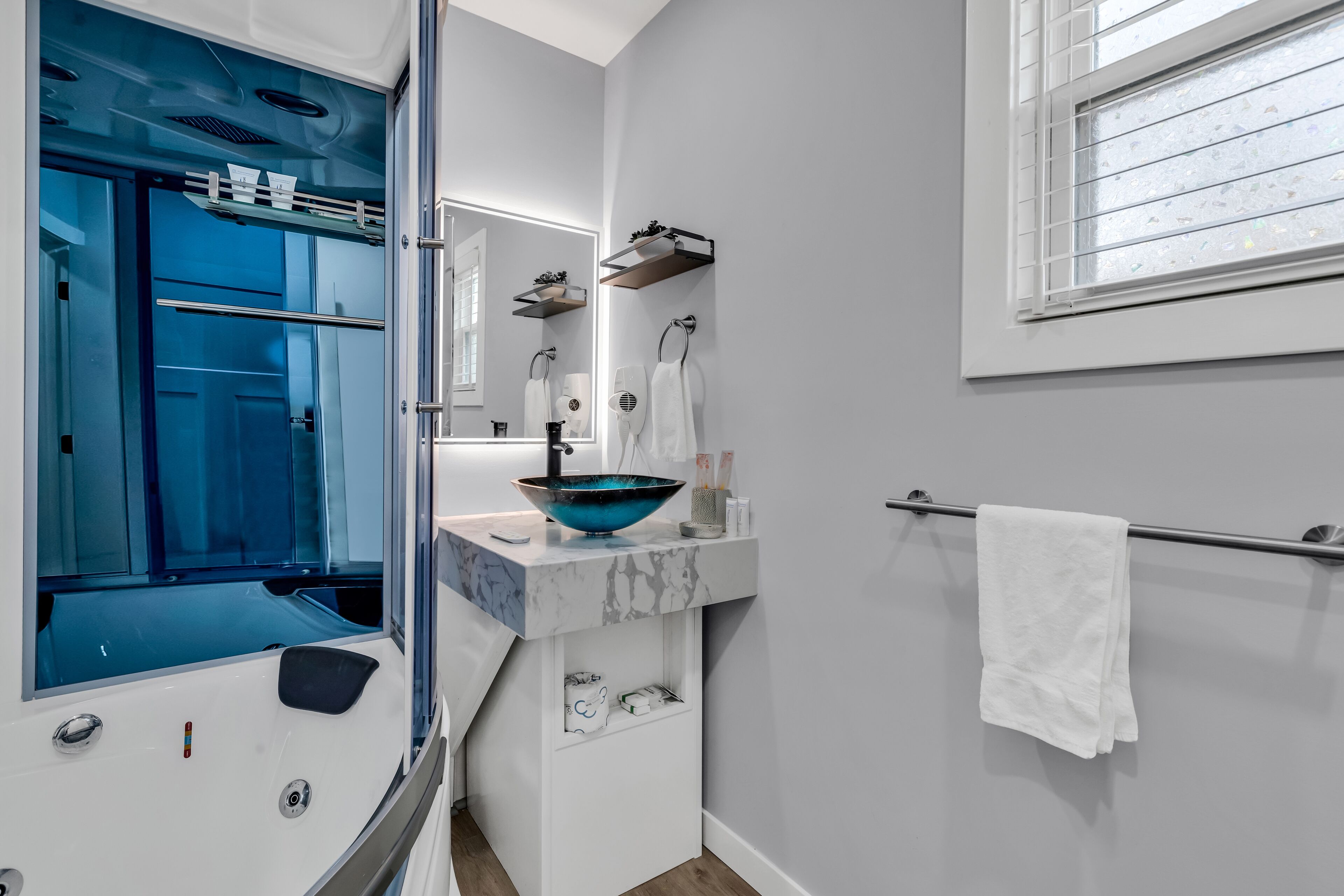 A modern bathroom with a glass-enclosed shower, a marble sink, and a towel rack.