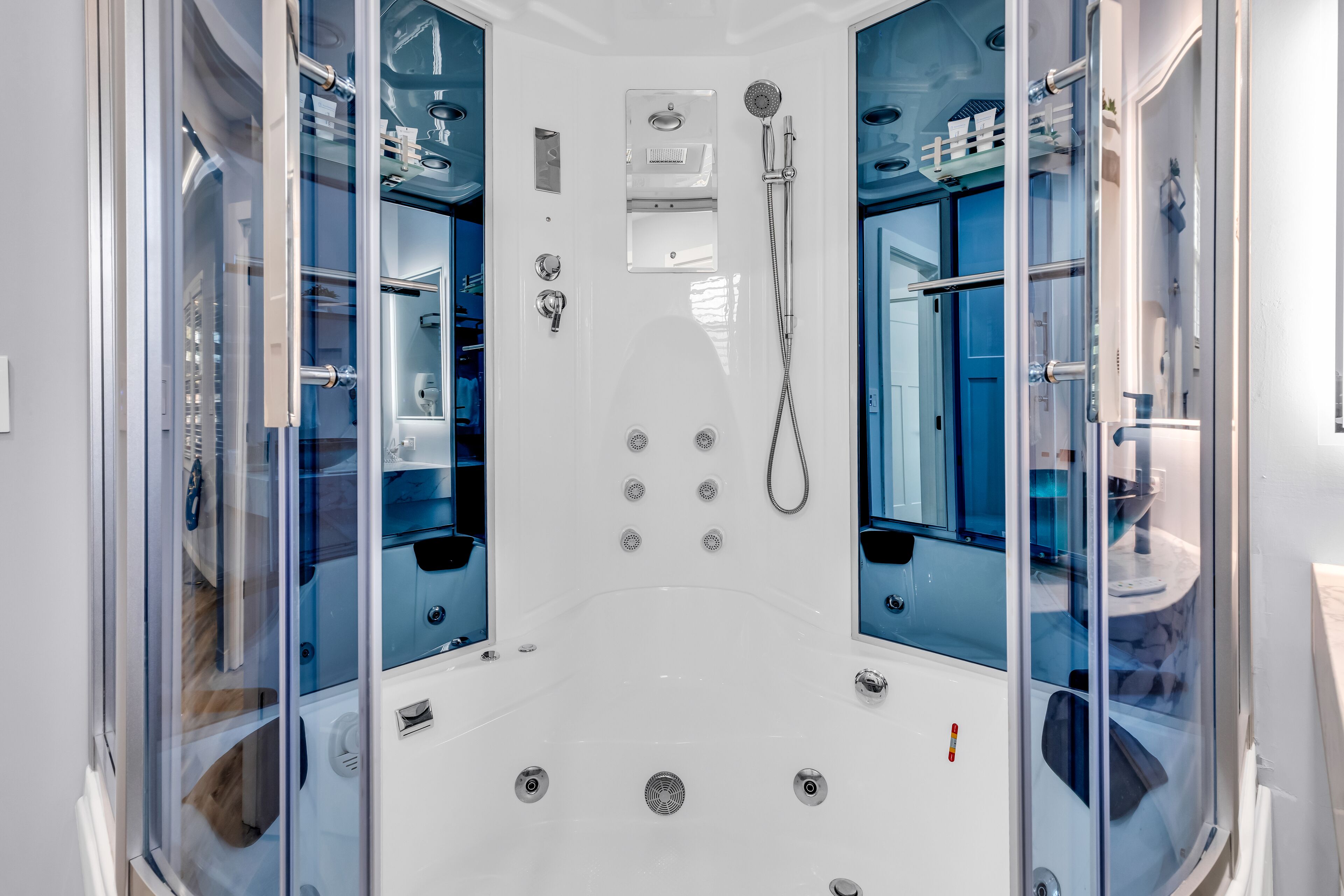 A modern bathroom with a glass-enclosed shower, built-in shelves, and a white vanity.