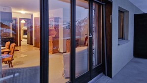 A modern interior with a dining area, kitchen, and a view through large glass doors. - Appartement LaForet 86 - La Tzoumaz, 4 Vallees (La Tzoumaz)