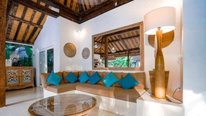 A modern living room with a beige sectional sofa, a glass coffee table, and a large floor lamp. - Villa Ketenangan (Ubud)